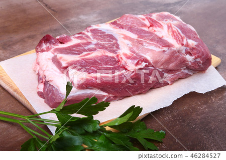 Raw pork neck chop meat with parsley herb leaves on a stone background. Ready for cooking. Raw pork neck chop meat with parsley herb leaves on a stone background. Ready for cooking. 46284527