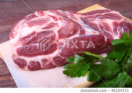 Raw pork neck chop meat with parsley herb leaves on a stone background. Ready for cooking. Raw pork neck chop meat with parsley herb leaves on a stone background. Ready for cooking. 46284531