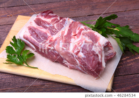 Raw pork neck chop meat with parsley herb leaves on a stone background. Ready for cooking. Raw pork neck chop meat with parsley herb leaves on a stone background. Ready for cooking. 46284534
