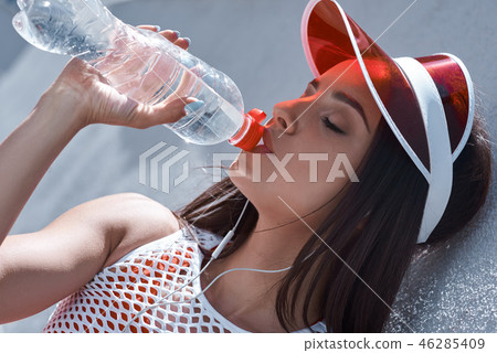 Young woman on roller skates and helmet drinking water. Stylish beautiful girl in shorts and a Young woman on roller skates and helmet drinking water. Stylish beautiful girl in shorts and a 46285409
