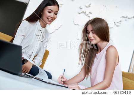 Young woman signing contract for a trip with agent 46285419