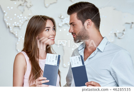 Joyful couple looking to each other and holding passport with flying tickets 46285535