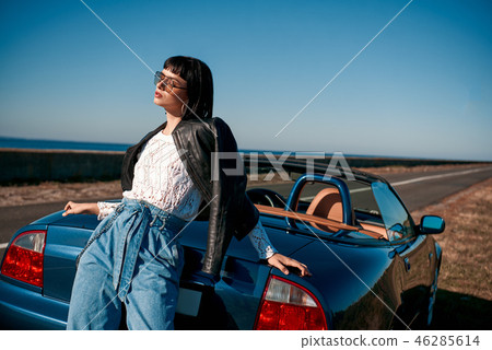 Close-up of young stylish woman with a haircut standing near roofless car 46285614