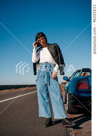 Young stylish woman in sunglasses with a haircut standing near roofless car 46285615