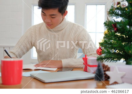 man writing note on notebook at home during christmas new year holiday celebration. 46286617
