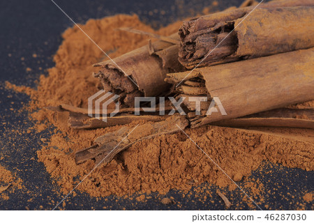 Sticks and ground ceylon cinnamon on dark background. Sticks and ground ceylon cinnamon on dark background. 46287030