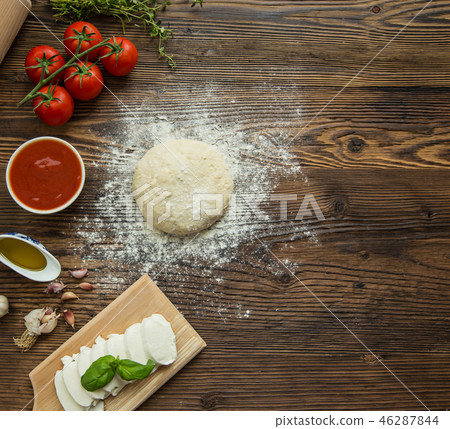 Pizza dough with ingredients on wooden background. Pizza dough with ingredients on wooden background. 46287844
