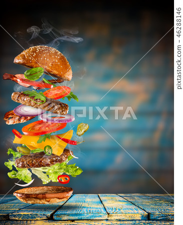 Big tasty burger with flying ingredients. Big tasty burger with flying ingredients. 46288146