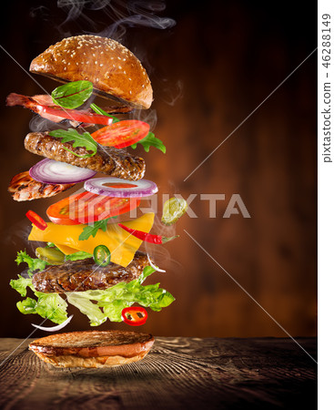 Big tasty burger with flying ingredients. Big tasty burger with flying ingredients. 46288149