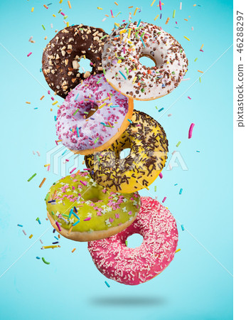 Tasty doughnuts in motion falling on pastel blue background. Tasty doughnuts in motion falling on pastel blue background. 46288297