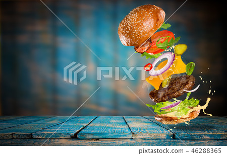 Big tasty burger with flying ingredients. Big tasty burger with flying ingredients. 46288365
