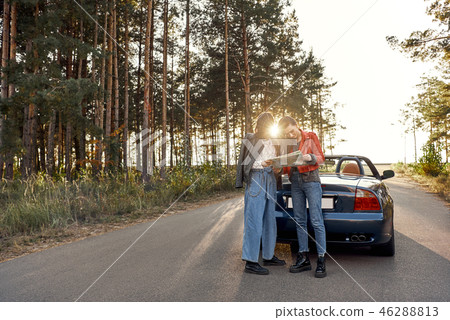 Two women trying to find the way on map near cabriolet Two women trying to find the way on map near cabriolet 46288813