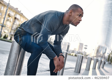 Urban sports. Young man runner resting after workout session on sunny morning. Male fitness model Urban sports. Young man runner resting after workout session on sunny morning. Male fitness model 46289407
