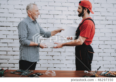 Worker Giving to Man Fixed Laptop in Workshop. Worker Giving to Man Fixed Laptop in Workshop. 46297350