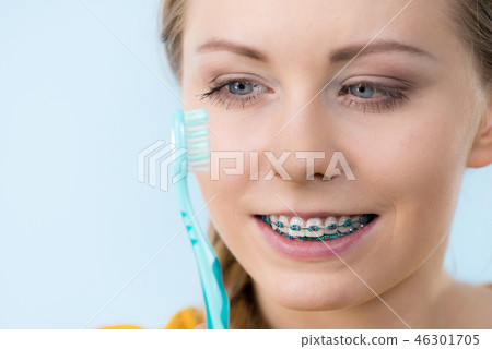 Woman smiling cleaning teeth with braces Woman smiling cleaning teeth with braces 46301705