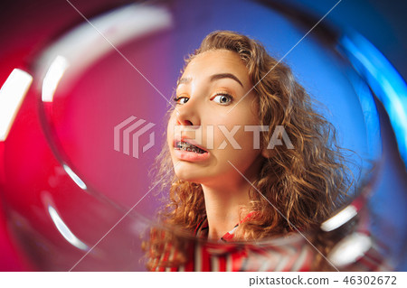 The surprised young woman in party clothes posing with glass of wine. 46302672