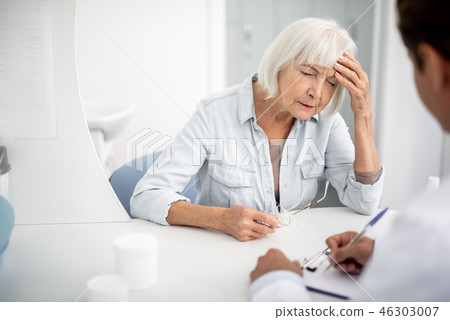 Elderly woman closing her eyes and suffering from headache Elderly woman closing her eyes and suffering from headache 46303007