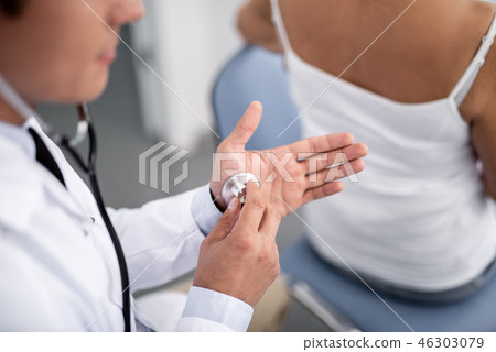 Calm doctor putting stethoscope on his hand Calm doctor putting stethoscope on his hand 46303079