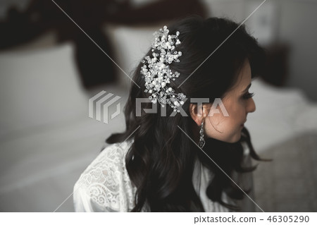 Gorgeous bride in robe posing and preparing for the wedding ceremony face in a room Gorgeous bride in robe posing and preparing for the wedding ceremony face in a room 46305290