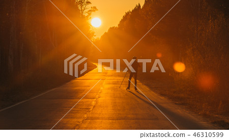 Training an athlete on the roller skaters. Biathlon ride on the roller skis with ski poles, in the 46310599