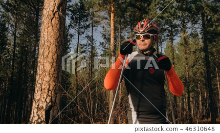 Training an athlete on the roller skaters. Biathlon ride on the roller skis with ski poles, in the 46310648