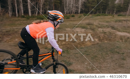 One caucasian children rides bike road track in dirt park. Girl riding black orange cycle in 46310670