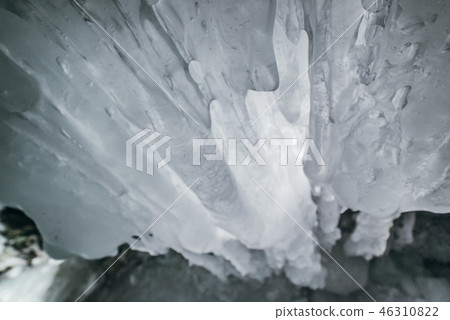 Winter Baikal. Olkhon Island. Ice grotto. Thick blue ice and icicles on the coastal rocks of Olkhon 46310822