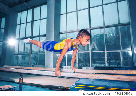 beautiful boy is engaged in sports gymnastics on a parallel bars 46310945