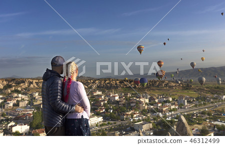 A young couple watches dozens of balloons fly  46312499