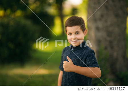 Cheerful boy spent time in park. Ten year old child smile and have fun Cheerful boy spent time in park. Ten year old child smile and have fun 46315127