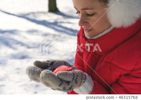 Hands in Knitted Mittens holding Steaming Cup of Hot Tea on Snowy Winter Morning Outdoors. Woman 46315768
