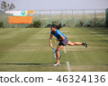 Junior tennis player serving on a natural turf court 46324136