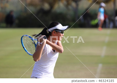 青少年網球運動員擊中天然草坪球場上的反手擊球 46324185