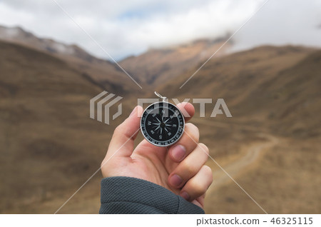 A male Hiker is looking for a direction with a magnetic compass in the mountains in the fall. Point 46325115