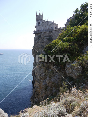 A dark, blue, calm sea with a rocky shore and a to A dark, blue, calm sea with a rocky shore and a to 46330555