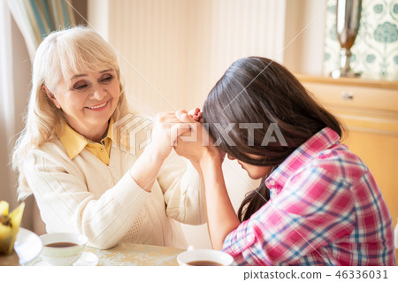 Daughter touches her foreheads with mother's hands intertwined with hers 46336031
