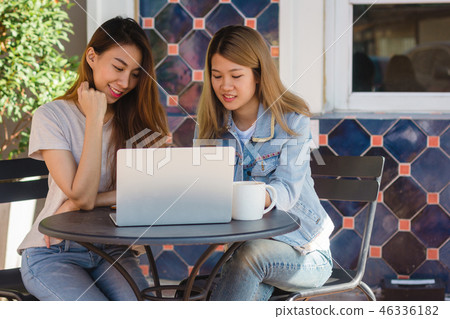 Asian women working together on laptop in cafe. Asian women working together on laptop in cafe. 46336182