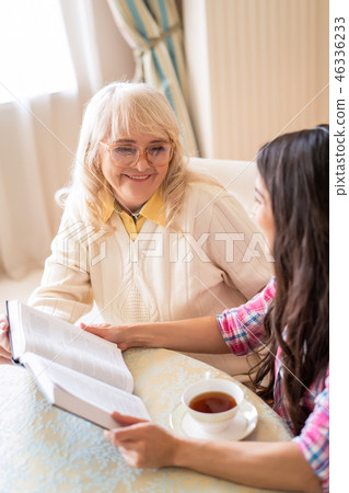 Senior mother and daughter read a book over a cup of tea Senior mother and daughter read a book over a cup of tea 46336233