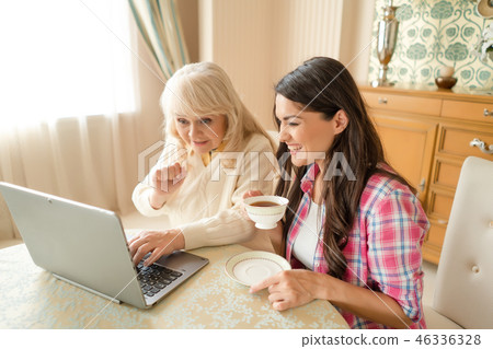 Senior mother together with her daughter waving at laptop camera. Senior mother together with her daughter waving at laptop camera. 46336328