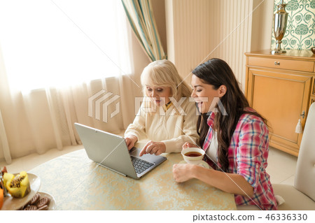 Senior mother together with her daughter waving at laptop camera. Senior mother together with her daughter waving at laptop camera. 46336330