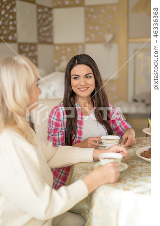 Portrait of pretty woman drinking tea and talking with her old mother Portrait of pretty woman drinking tea and talking with her old mother 46336368