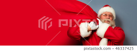 Santa Claus is holding a bag of gifts 46337425