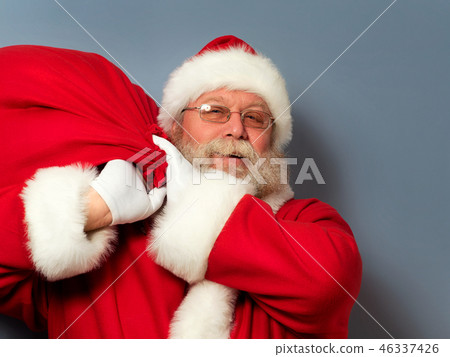 Santa Claus is holding a bag of gifts 46337426