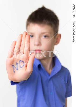 Teen little boy making stop sign with word no on open palm 46337664