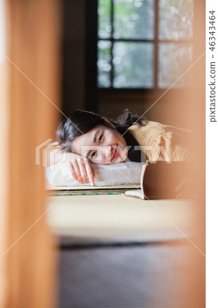 Young woman reading a book lying on tatami at travel destination 46343464