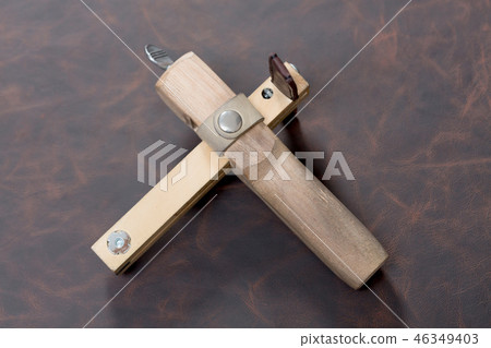 The strap cutter on brown leather background. 46349403