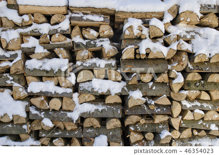 Chopped firewood on a stack in snow. Front view. 46354023