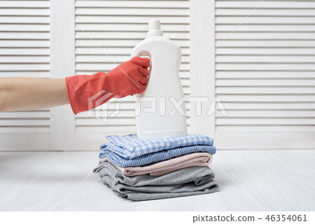 Stack of folded clothes and detergent bottle 46354061