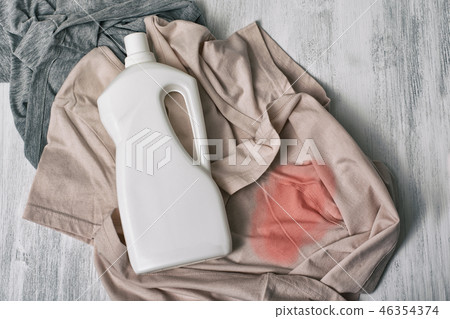 Clothes with stains and a bottle of detergent 46354374