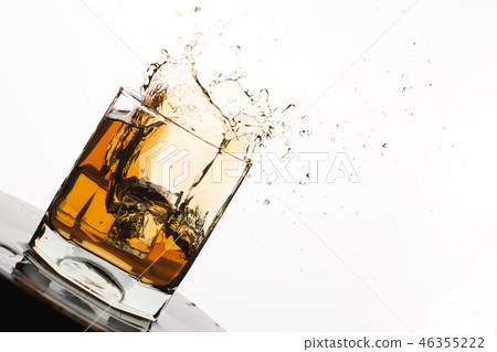 Tilted Glass of splashing whiskey with ice Tilted Glass of splashing whiskey with ice 46355222